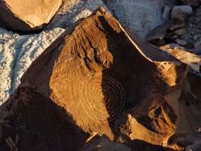 spiral petroglyph bisected by shadow