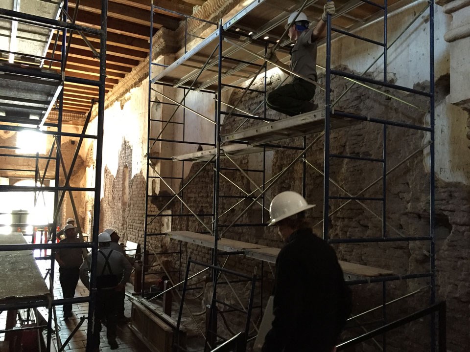 scaffolding and workers inside adobe church