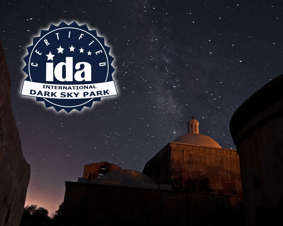 See the Milky Way above the Tumacácori mission church. international dark sky park logo with night sky and dome