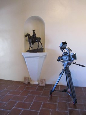 video camera on a tripod next to bronze statue of horseback kino