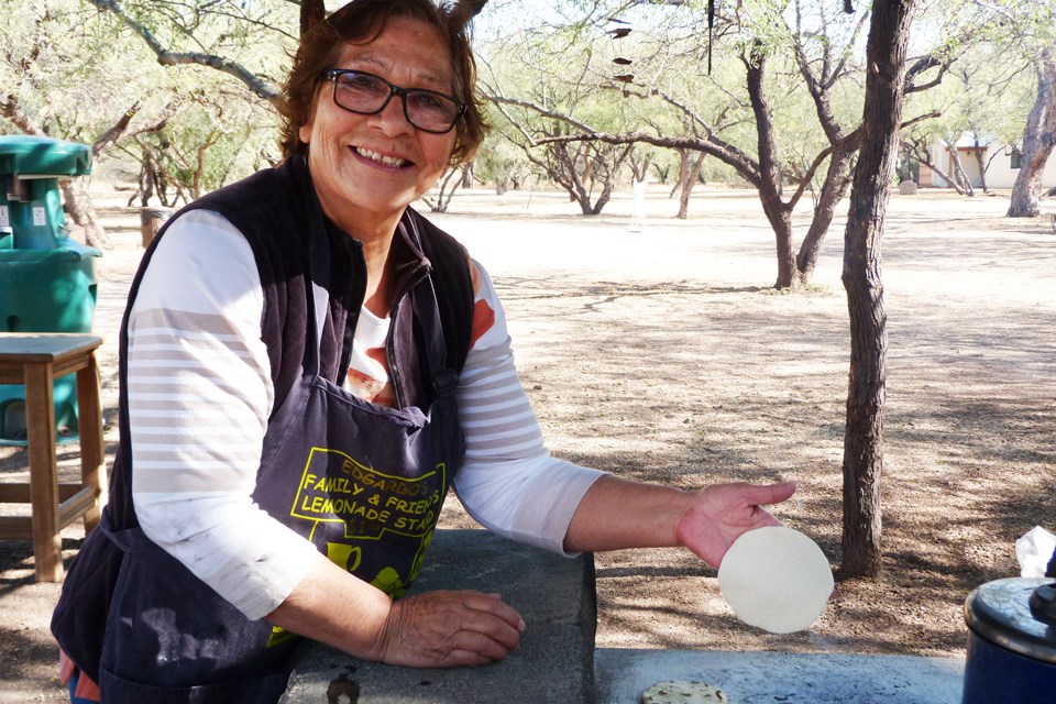 Carolina Arizpe, tortilla demonstrator, out outdoor kitchen with corn tortilla ready to place on the comal.