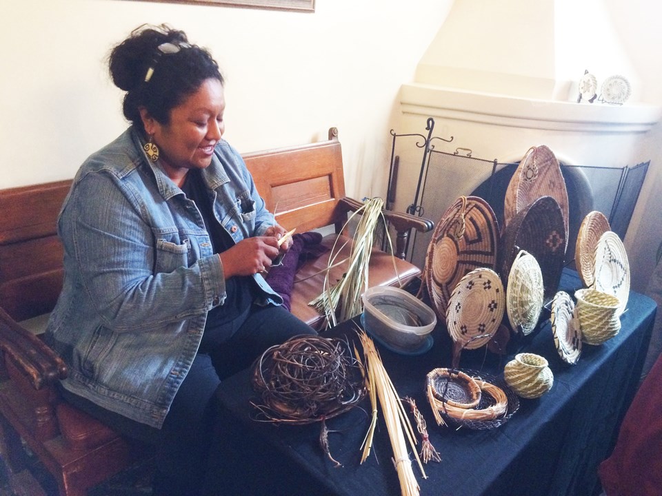 Demonstrator with table full of finished baskets and materials.