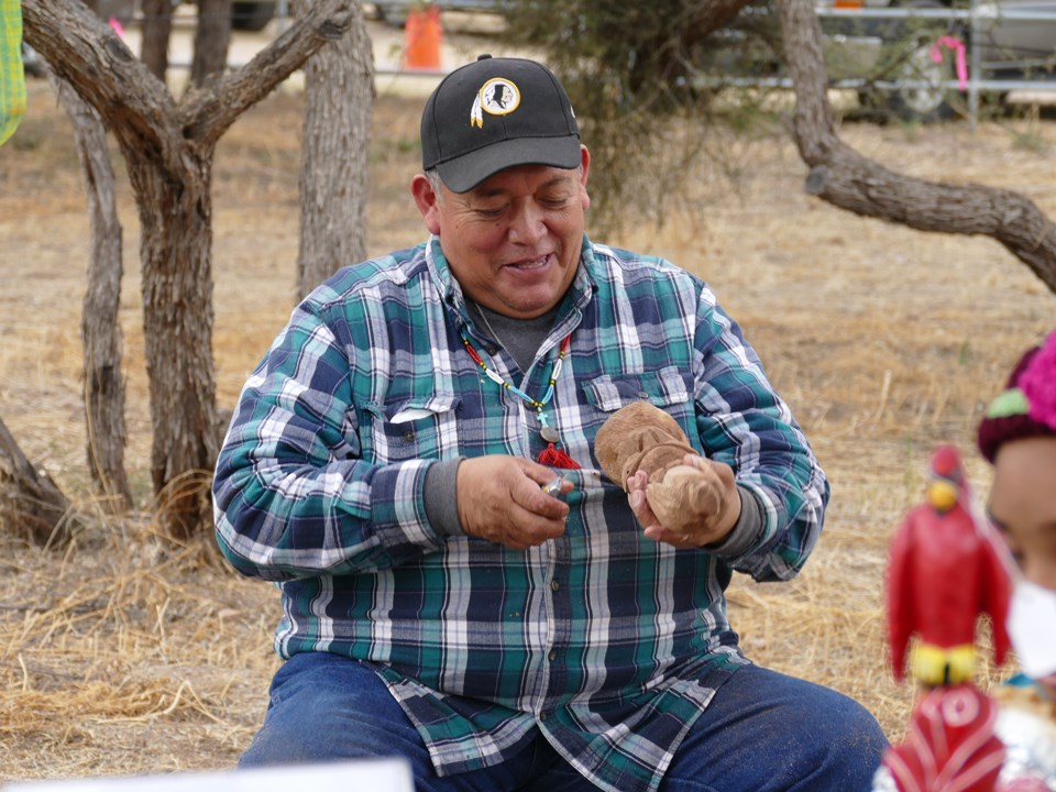 Demonstrator carving a piece of wood.