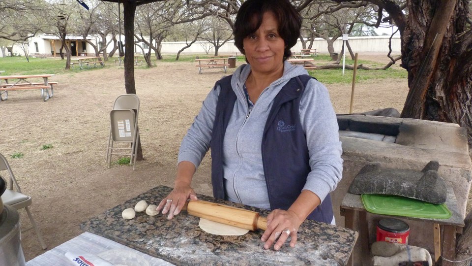 Carmen Espinoza, tortilla demonstrator, at outdoor kitchen with masa and rolling pin.
