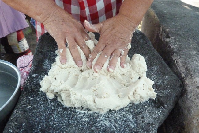 Mixing corn masa on a stone metate.