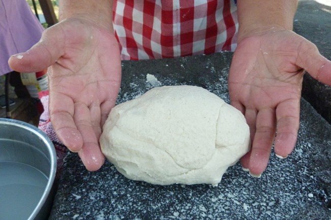 Closeup of corn masa, fully mixed and incorporated, on a stone metate.