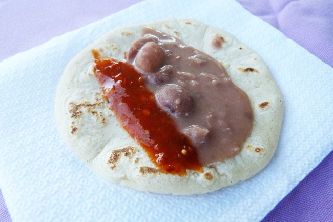Closeup of finished tortilla with beans and salsa.