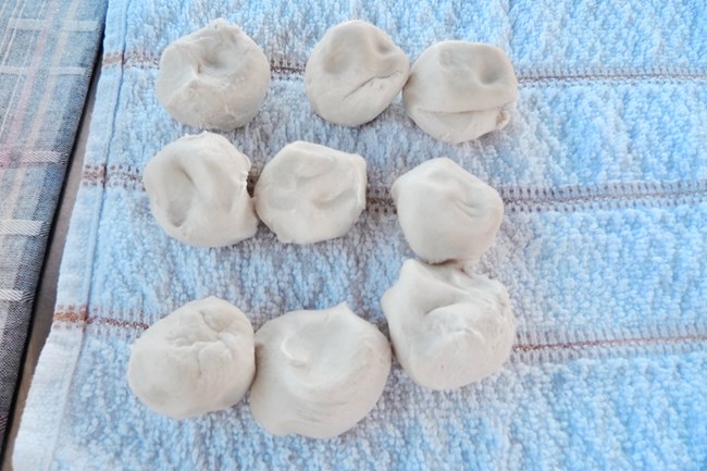 Golf ball sized dough laying on a kitchen towel.