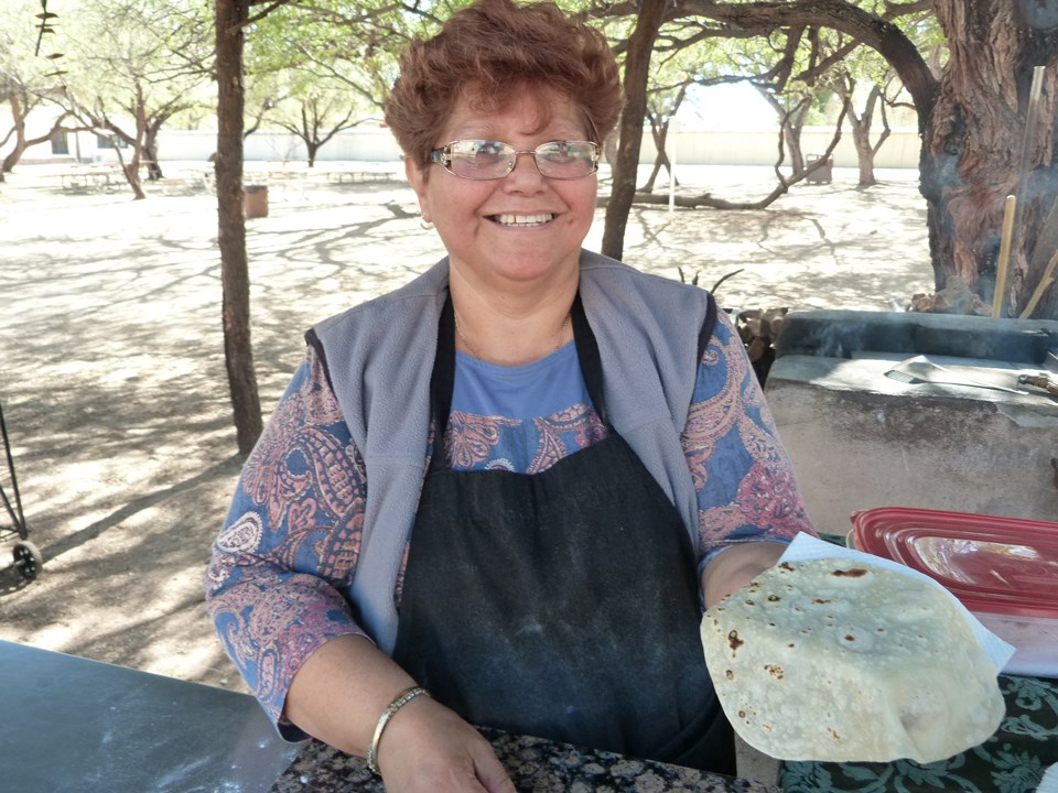 Sandra García, tortilla demonstrator, with finished tortilla at outdoor kitchen.