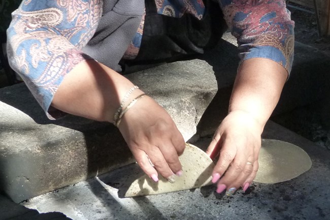 Placing a flour tortilla on the comal.