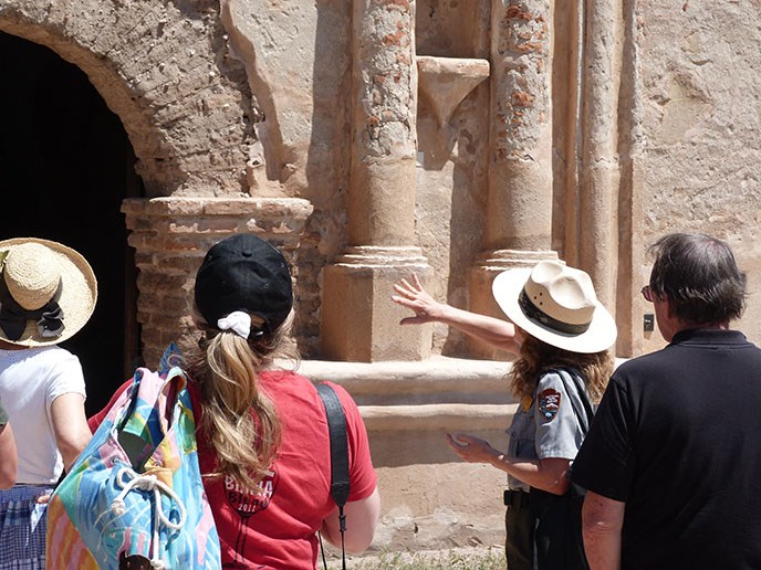 ranger giving guided tour to visitors in front of church::join a ranger for a guided tour