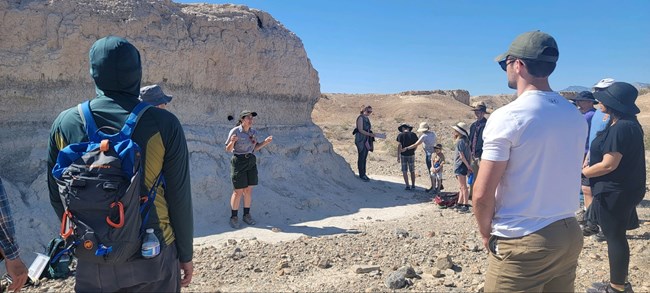 A park ranger speaking to a group of hikers within desert badlands