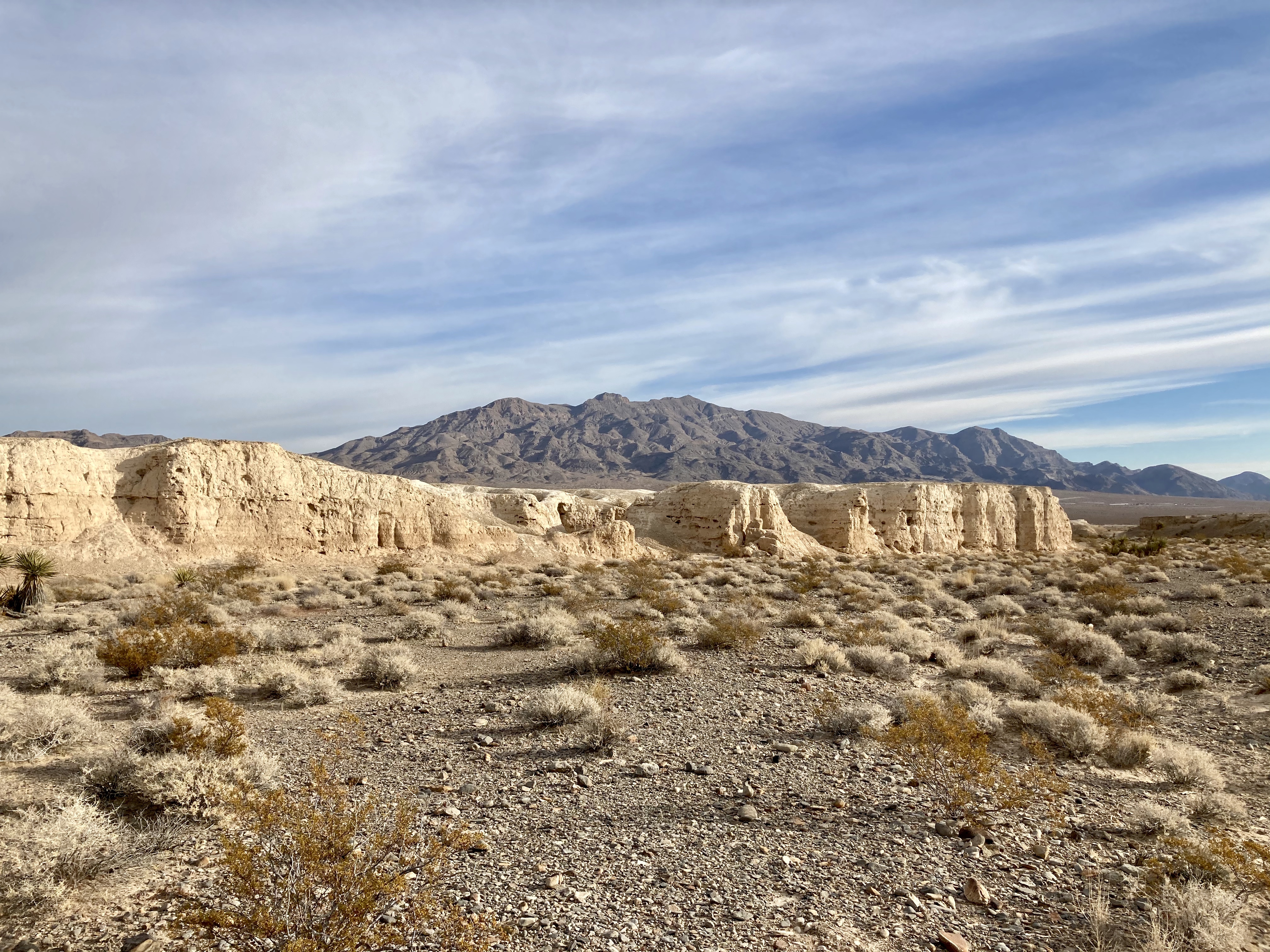 TUSK Durango Sunlit badlands within a desert wash, surrounded by mountains