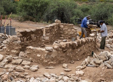 Two masons work on building the replica room, which is halfway done.