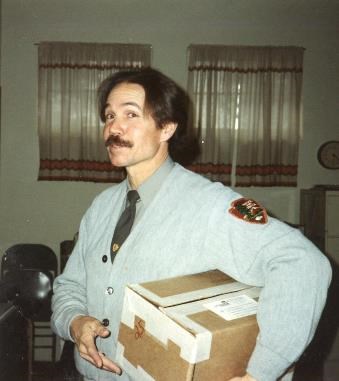 A ranger in an NPS sweater holding a box.