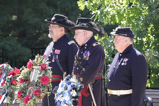 Three reenactors in Civil War uniforms with wreaths