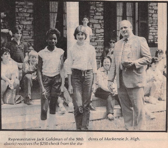 Black and white photograph of a man and middle school children posed in a group.