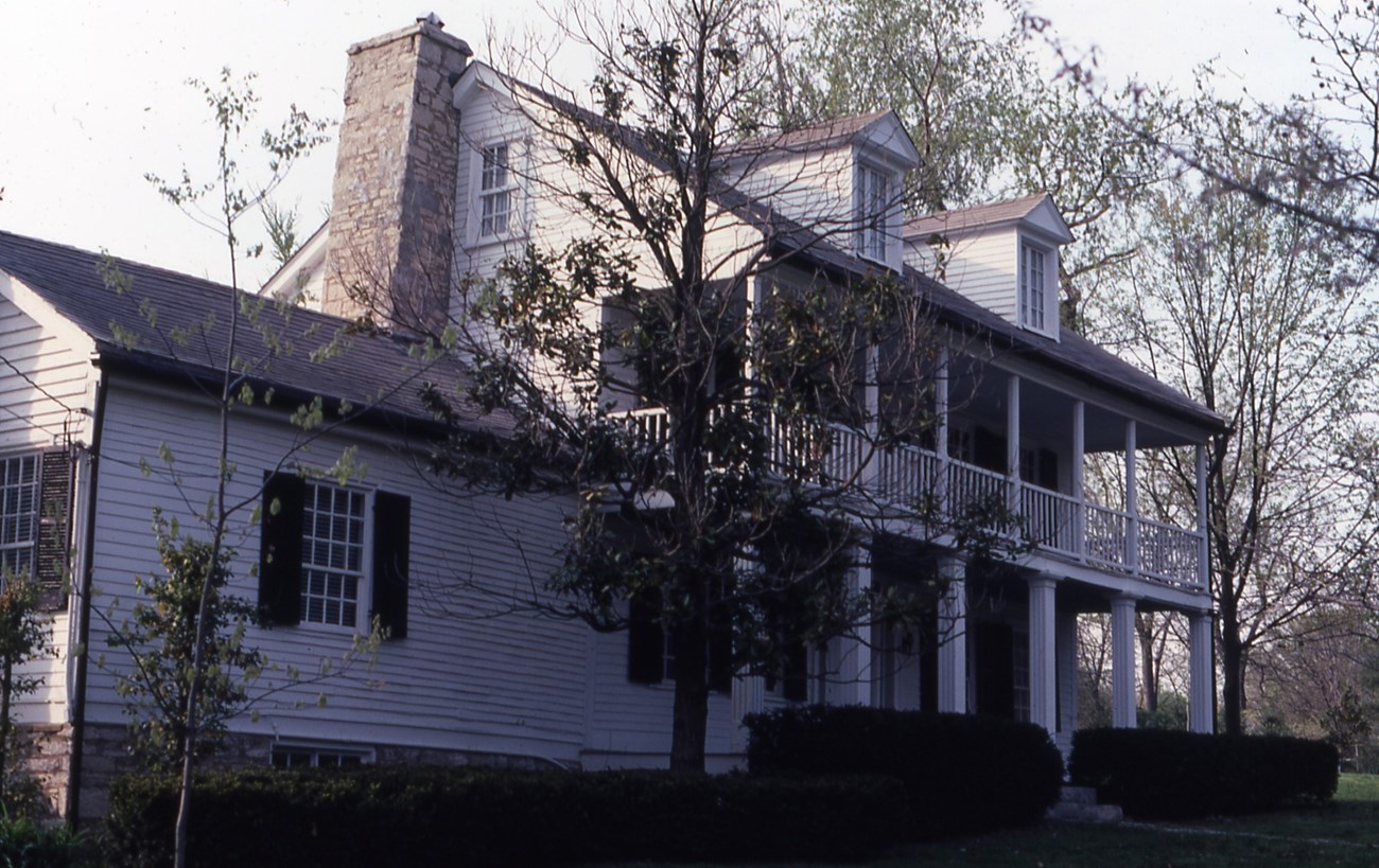 Color photograph of a white 19th century frame house with columns and dormers