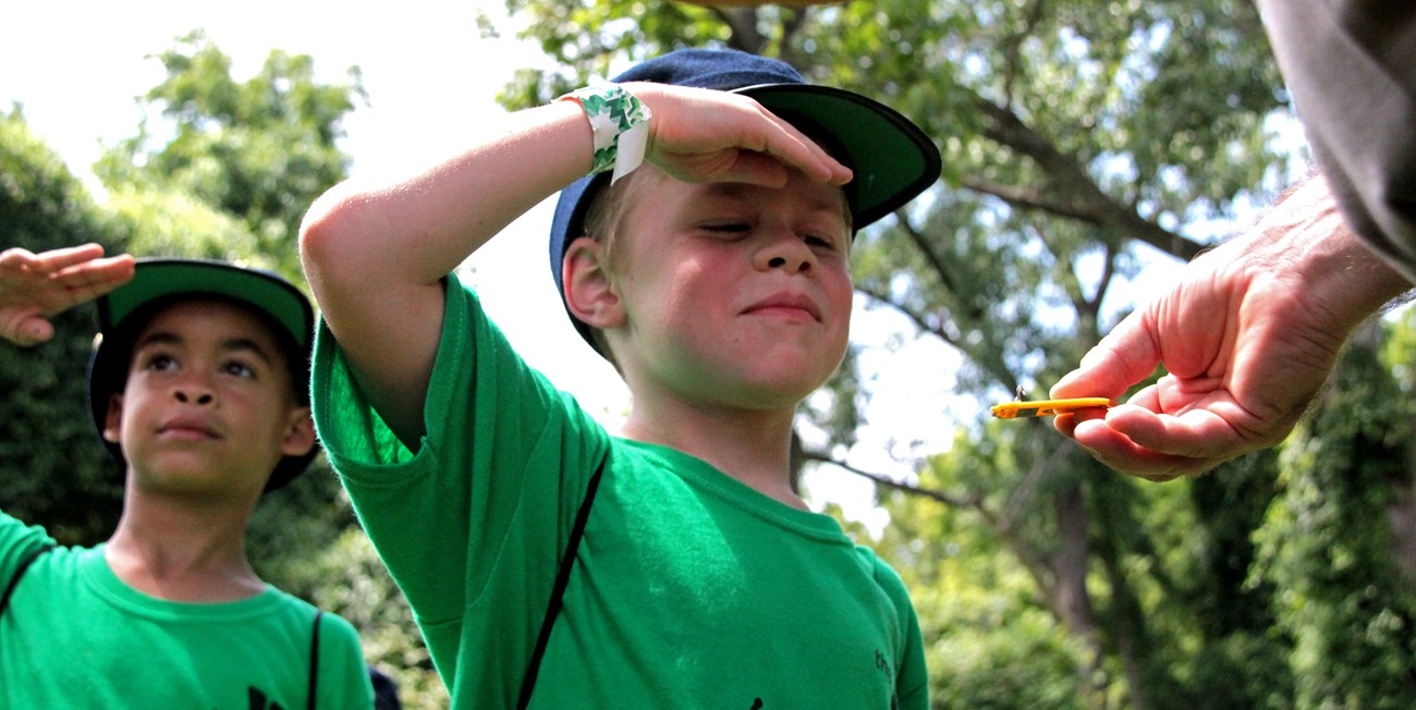 photo of two boys in civil war hats saluting and receiving a junior ranger badge