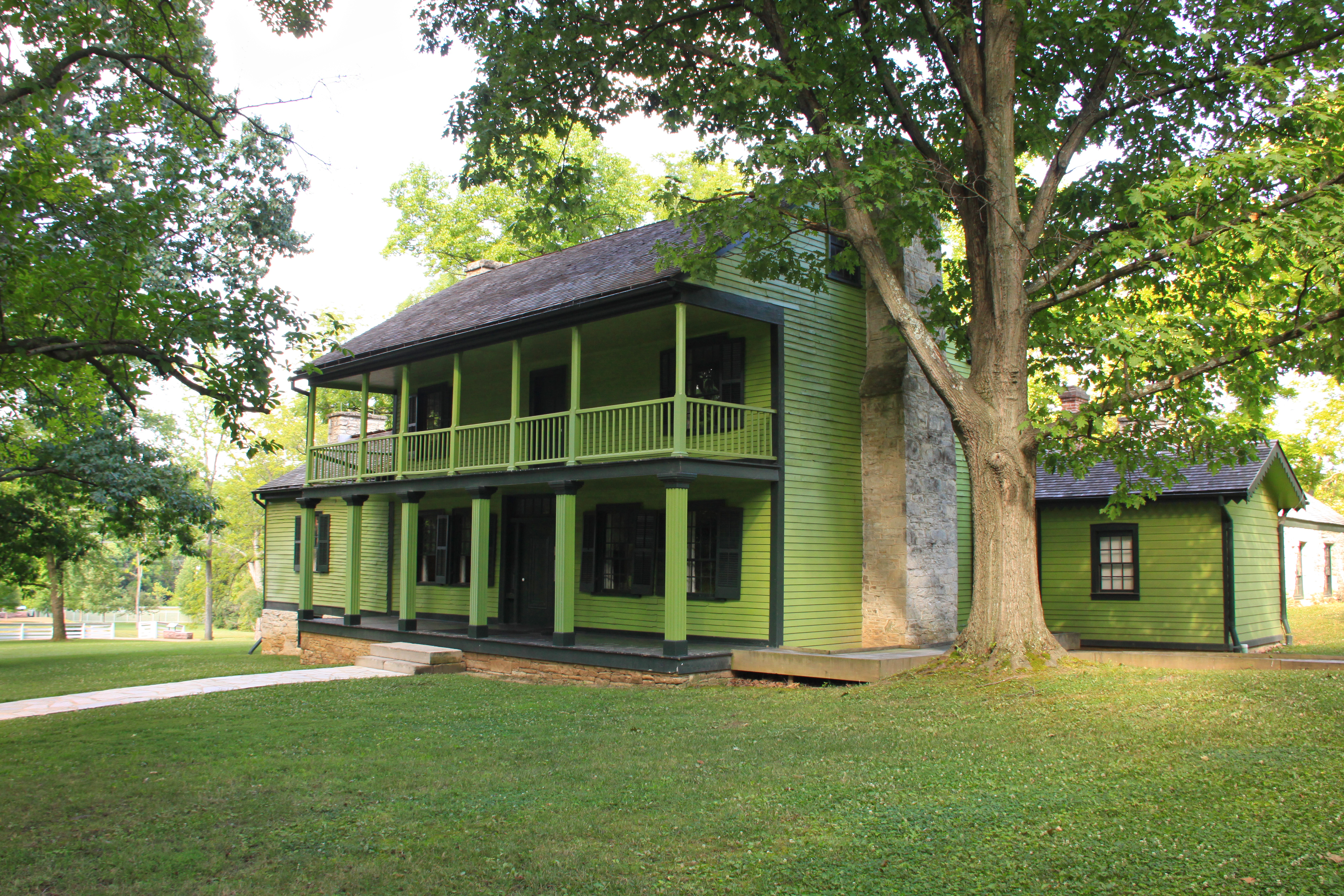 White Haven in the Summer green two-story house with porch surrounded by trees