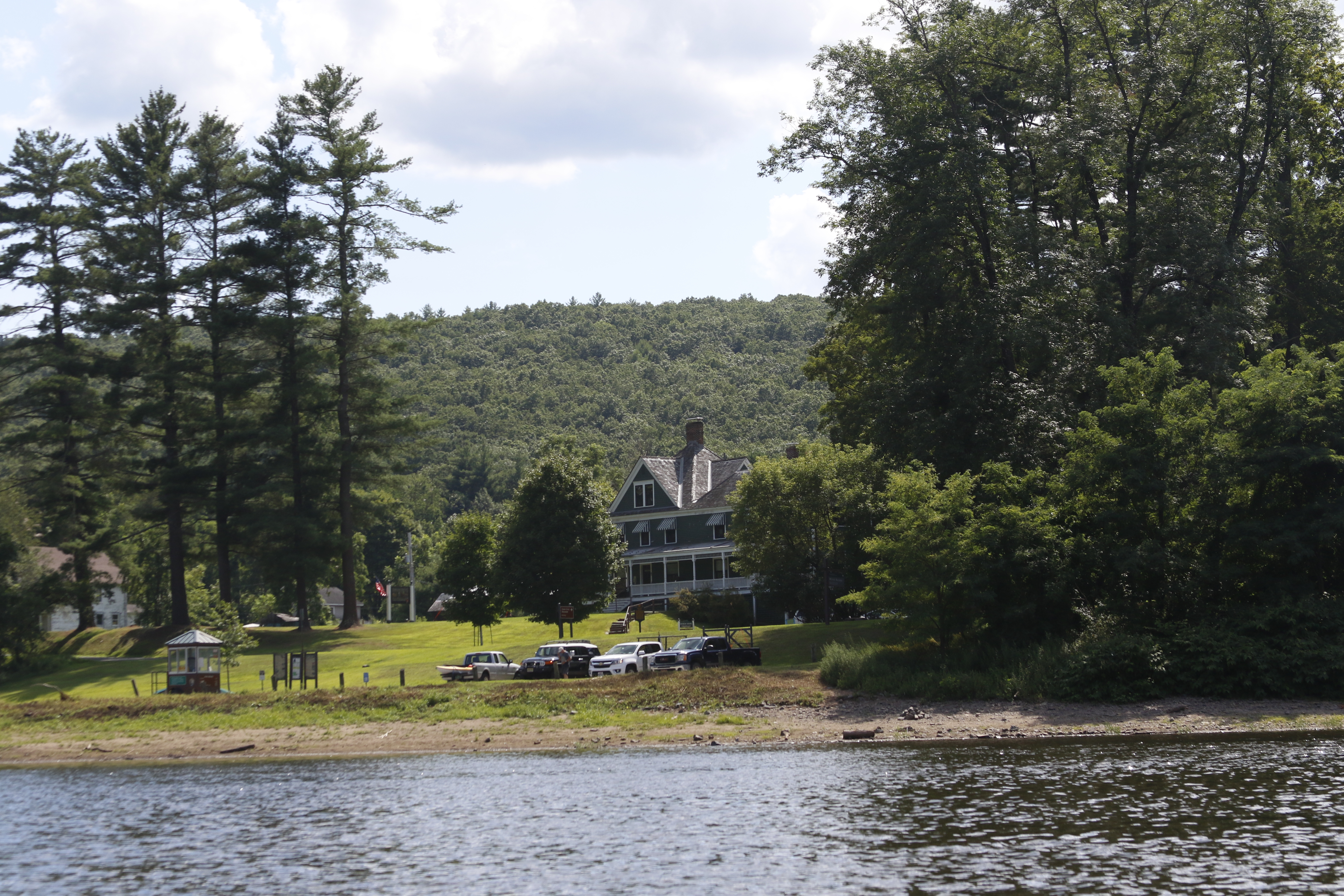 Two-story house on lush bank of river. In front of house is a public river access.