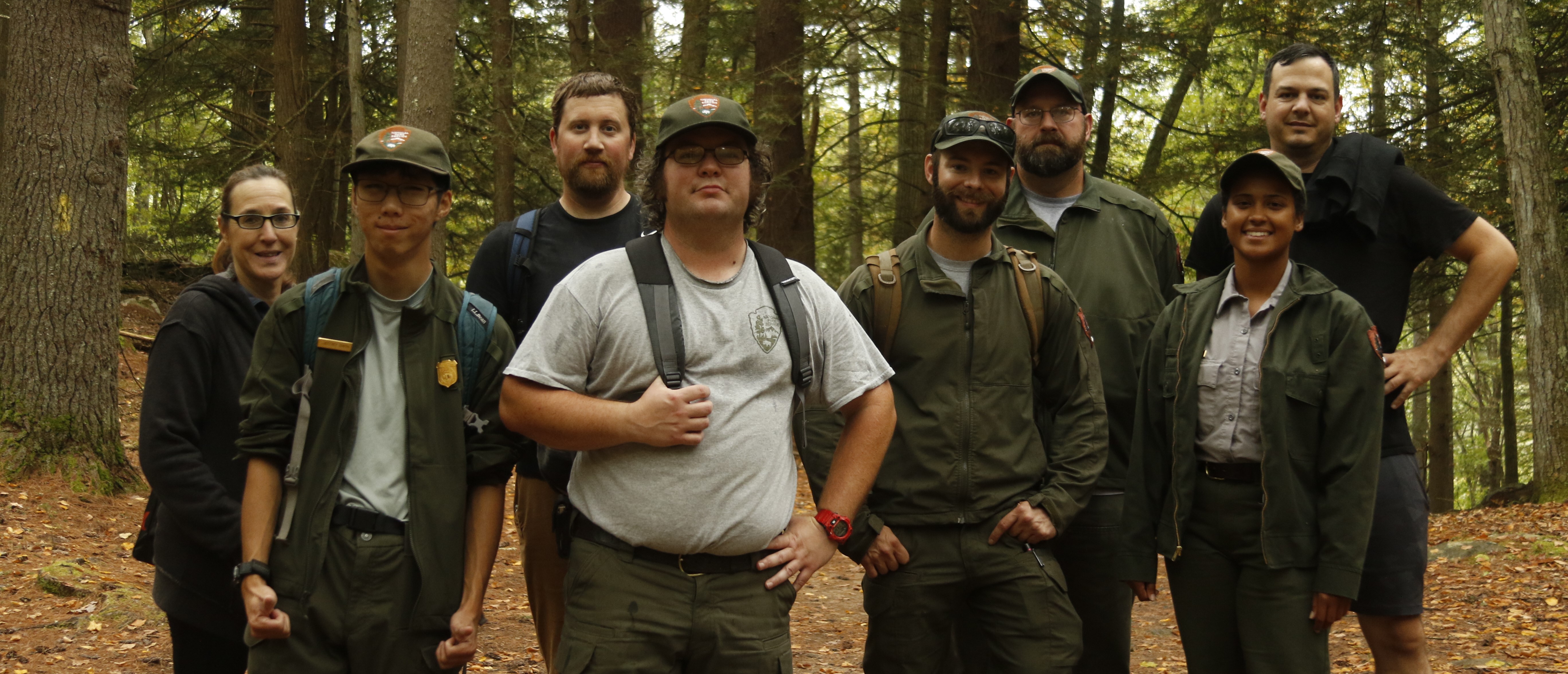 group of park rangers, some in uniform and some in civilian clothing, in a forest