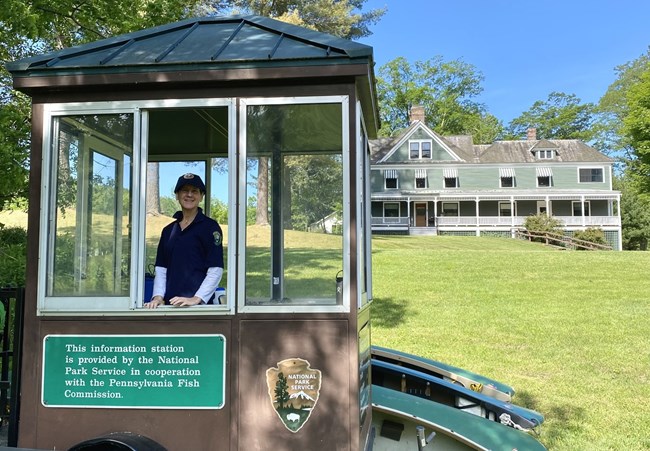 Volunteer stands in river kiosk with Zane Grey Musuem in background