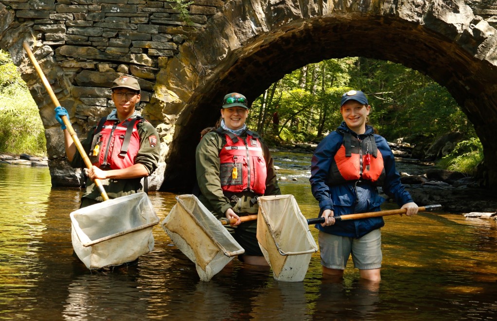 The people standing in a river with nets.