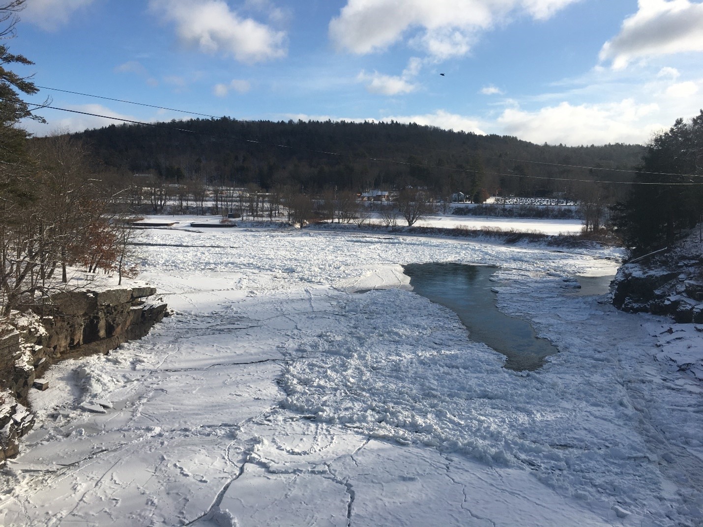 White snow and ice on the Delaware River in the center of the picture with trees on either side. White snow and ice on the Delaware River in the center of the picture with trees on either side.