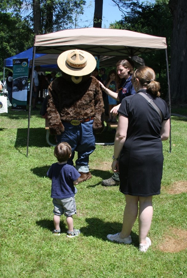 Smokey Bear bending over to speak with a small child.