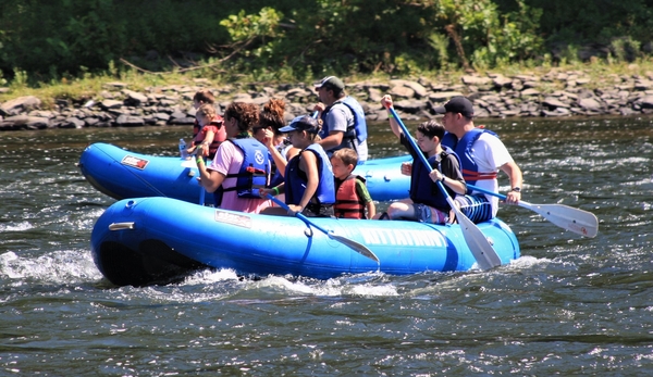 Visitors in raft wearing life jackets. Visitors in raft wearing life jackets.