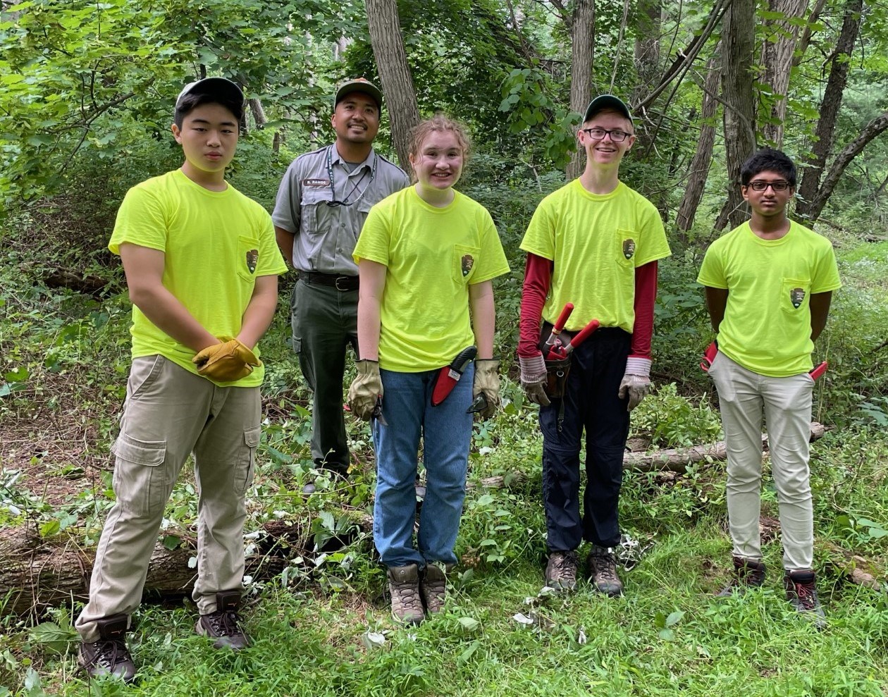 YCC Crew photograph, 4 young people stand in the forest wearing uniform shirts, crew leader stands behind