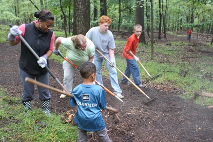 Volunteers raking fresh mulch along a trail Volunteers raking fresh mulch along a trail