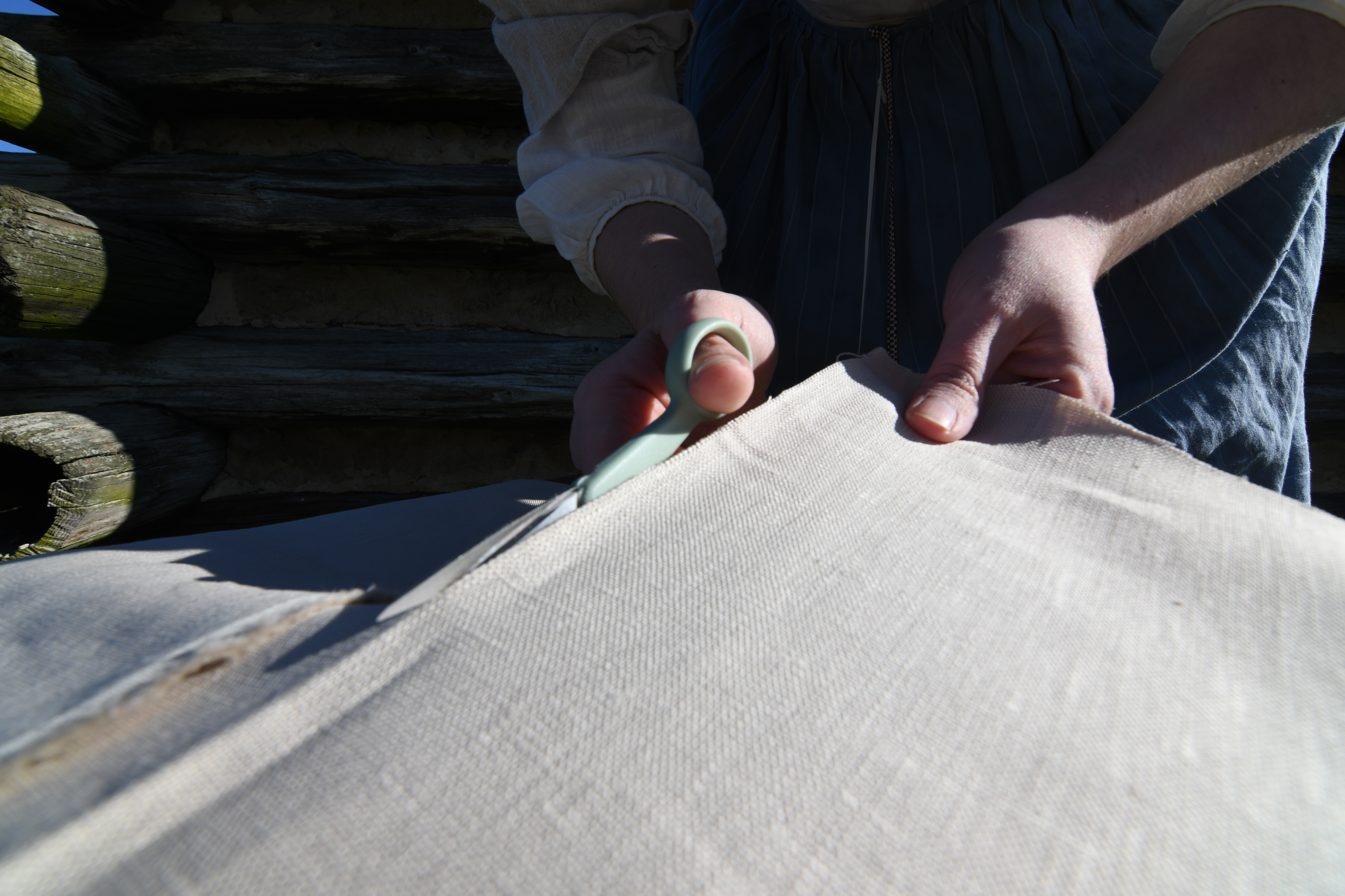 photograph, outdoors, closeup of women hands cutting fabric with scissors