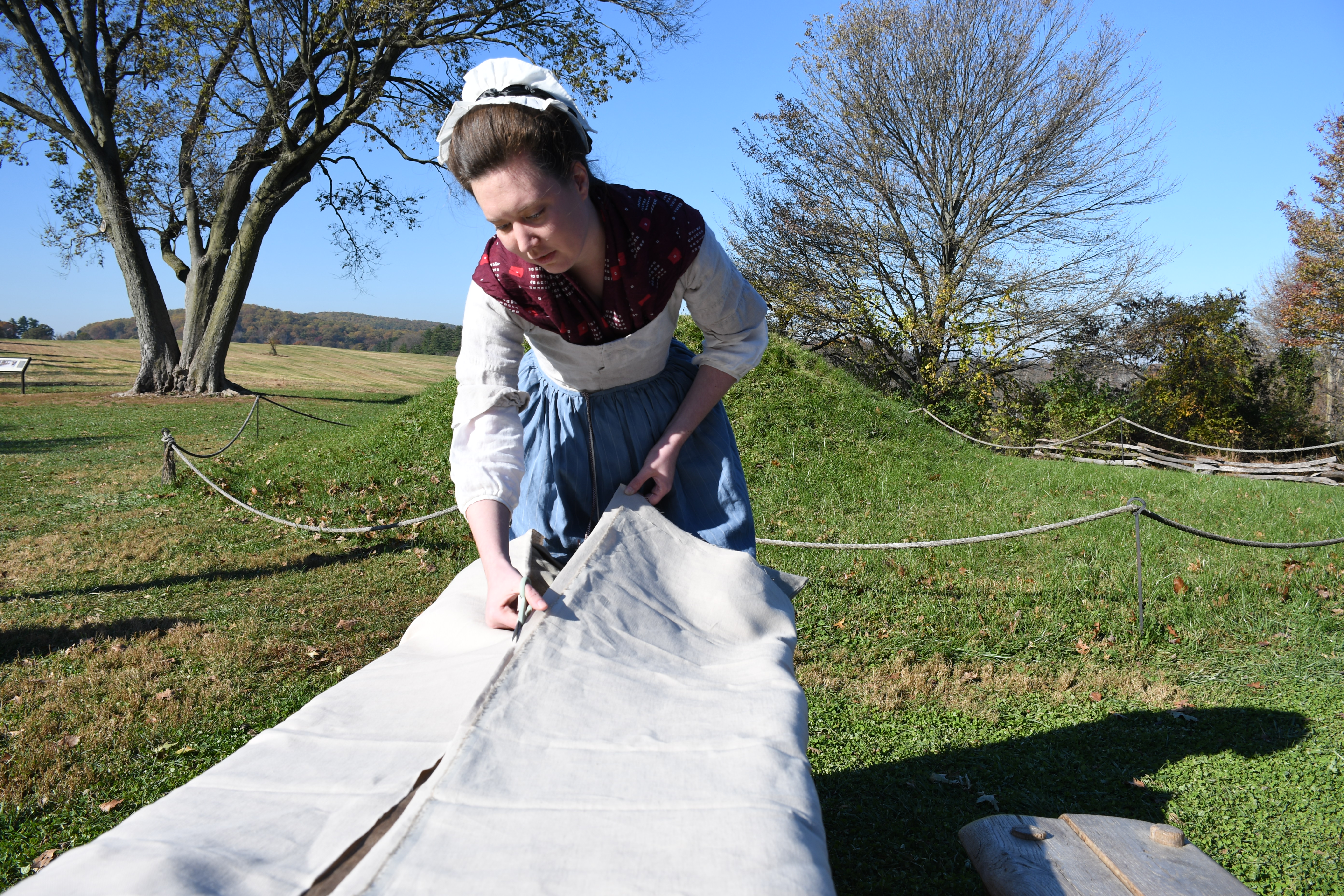 photograph, outdoors, woman cuts fabric with scissors