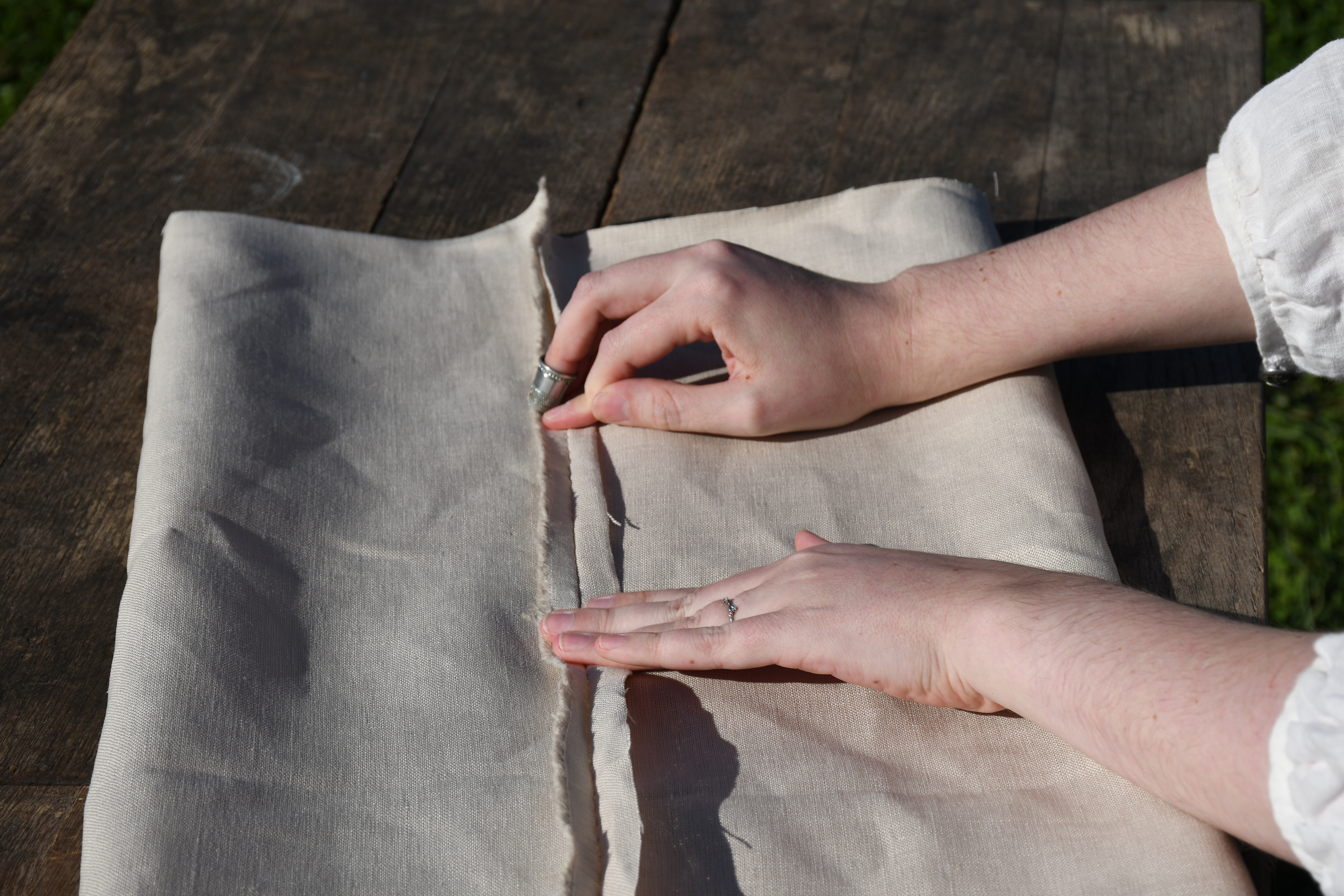 outdoors, photograph, woman's hands fold and press the long hem