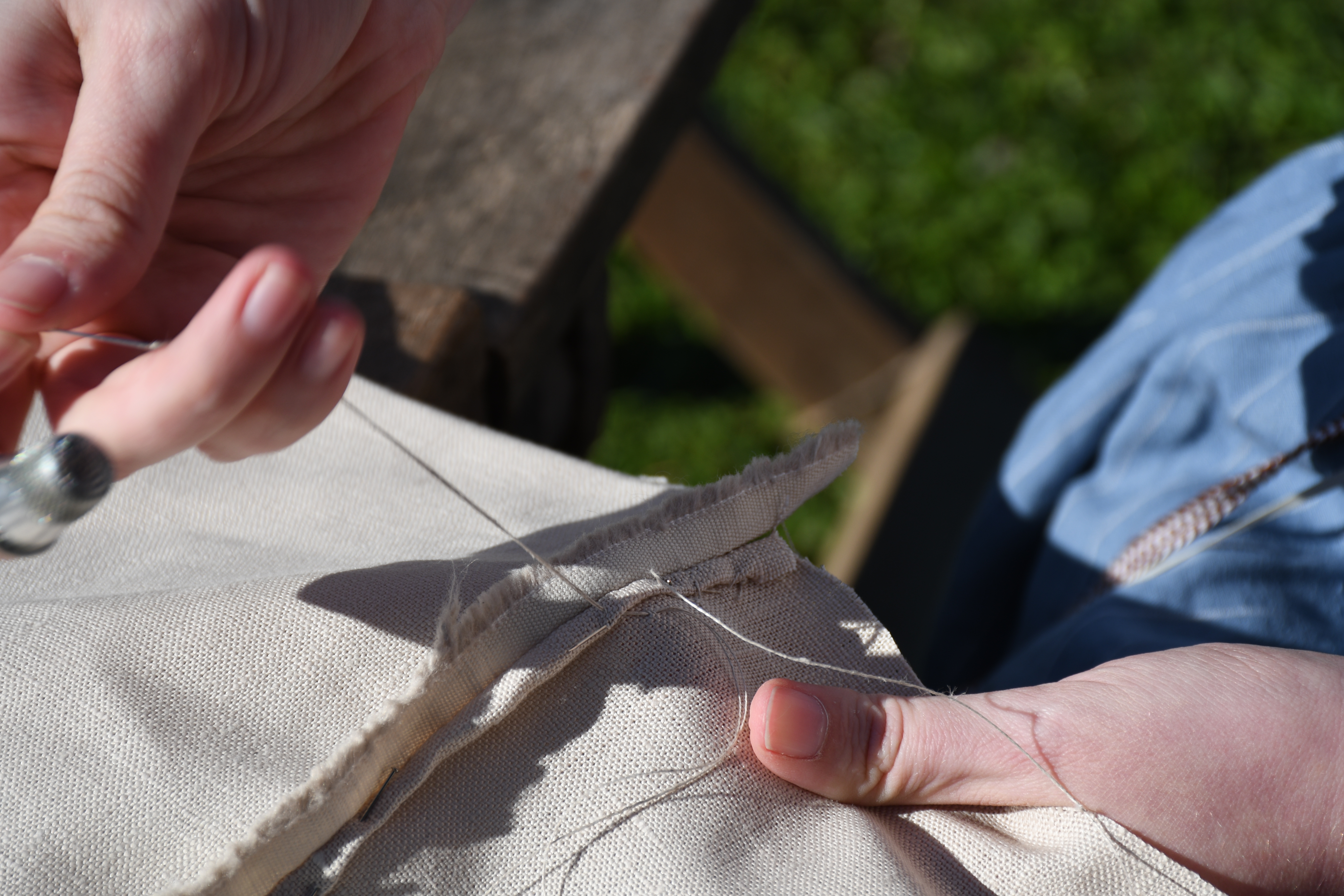 photograph, outdoors, closeup of woman's hands finishing a whipstitch