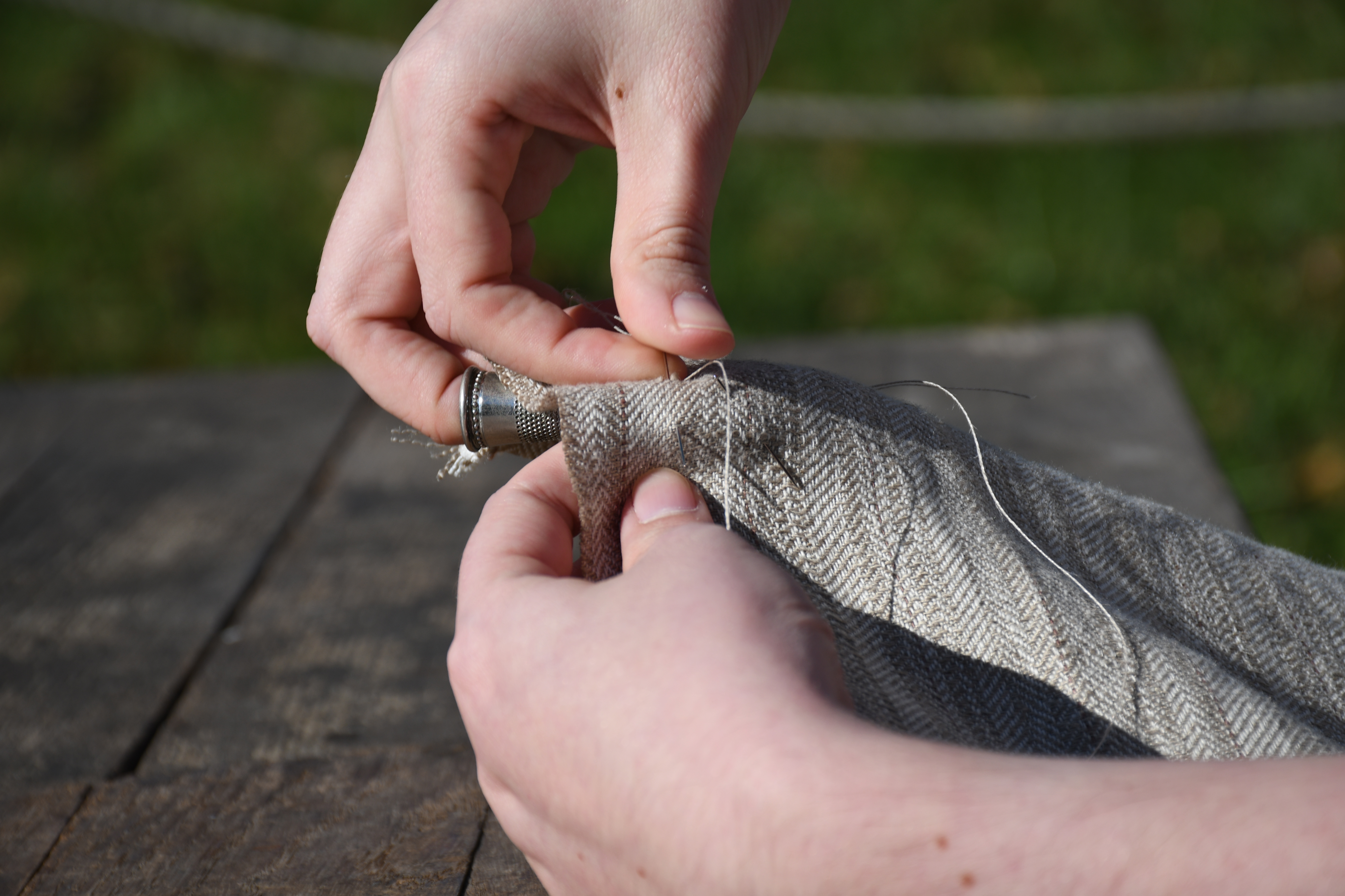 photograph, outdoors, closeup of woman's hands stitching an end seam