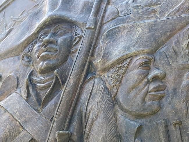 closeup detail, bronze sculpture, faces, muskets