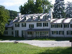 A white, two story building surrounded by trees.