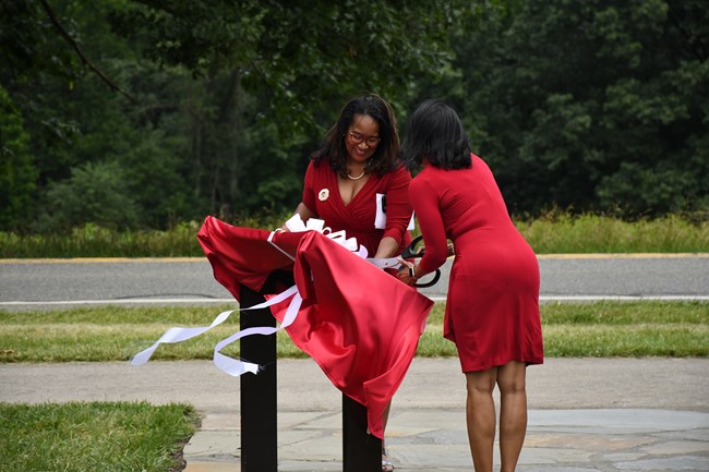 Two Sorors of Delta Sigma Theta Sorority ceremonially cut the ribbon and remove the veil