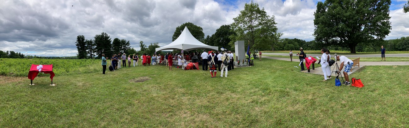 a tent with a crowd of people next to the patriots of african descent monument