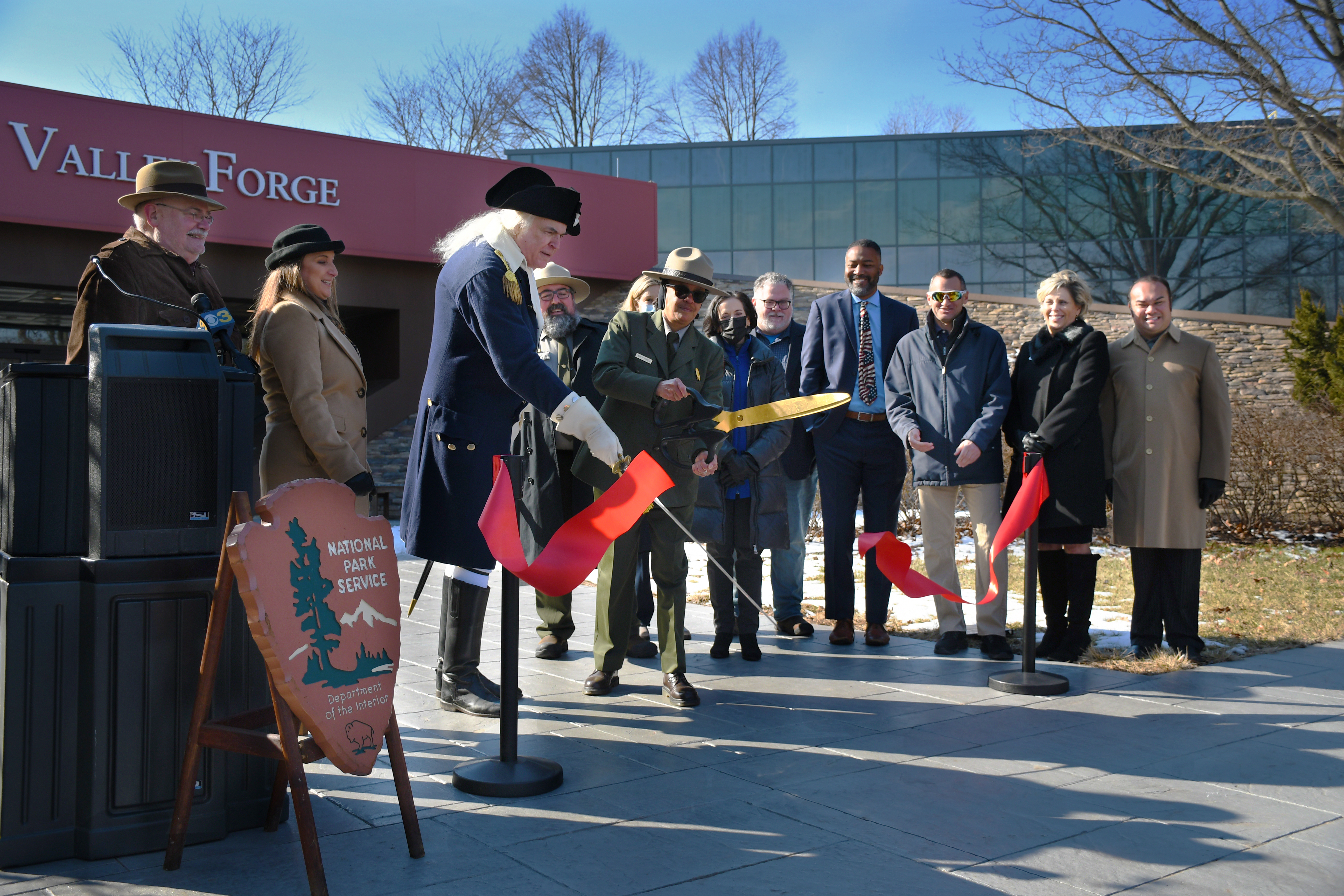 uniformed park ranger cuts a red ribbon in front of the visitor center