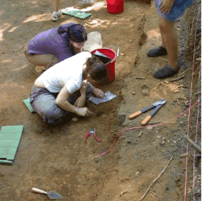 Two women digging for archaeological remains.