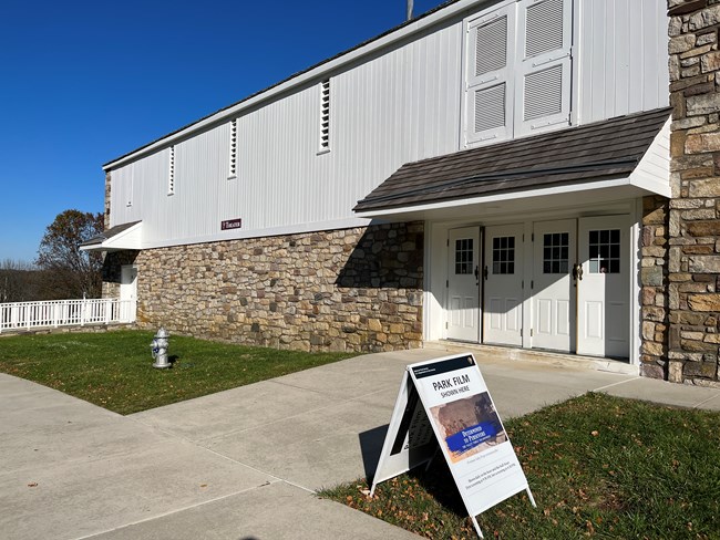 A barn-like structure with stone foundation and white wood plank siding.