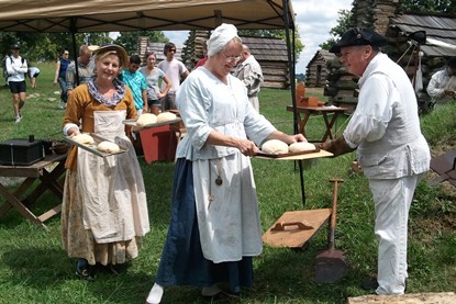 Living history volunteers take freshly baked bread out of the historic bake oven Living history volunteers take freshly baked bread out of the historic bake oven