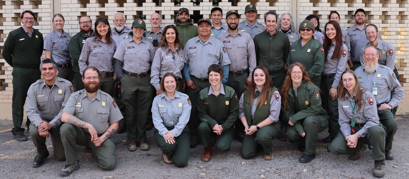 A large group of park rangers stand together for a group photo.