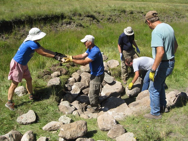 Five Los Amigos volunteers stacking rocks.