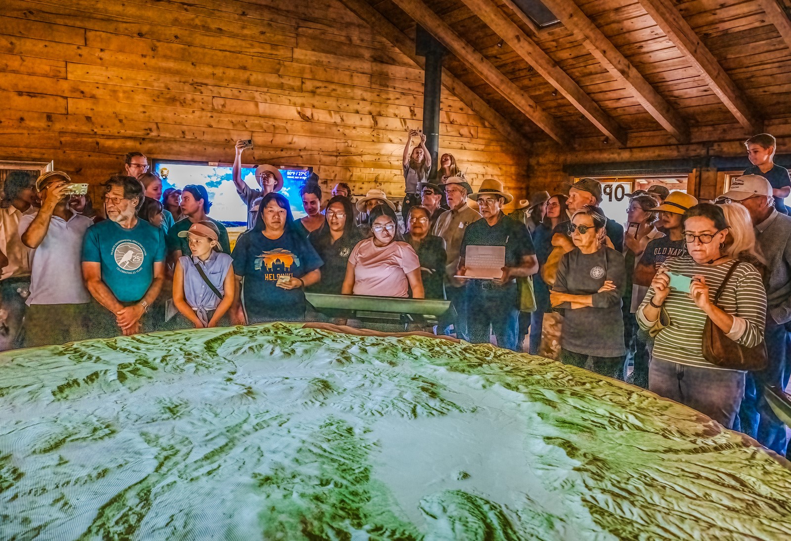 Exhibit Premiere A crowd of people stand around a circular 3D map exhibit inside of a visitor center.