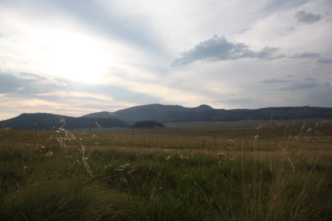 Late afternoon sun setting over a vast grassland valley